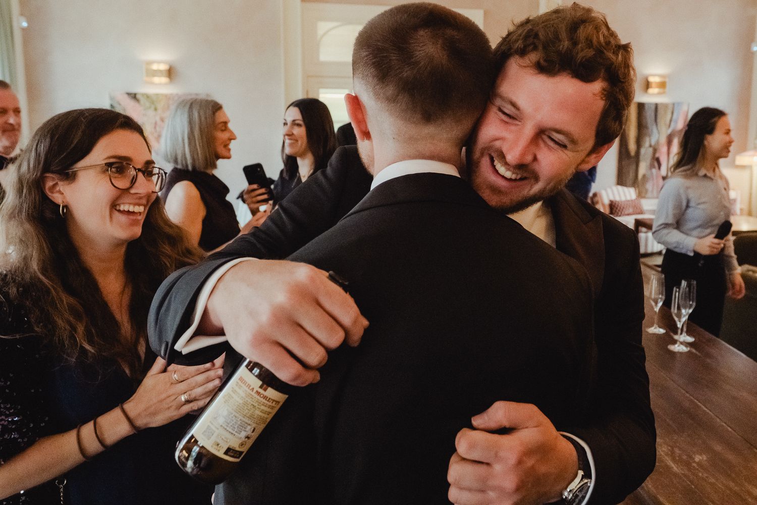 People sharing joyful moments and hugs at a formal gathering in an industrial-chic venue.
