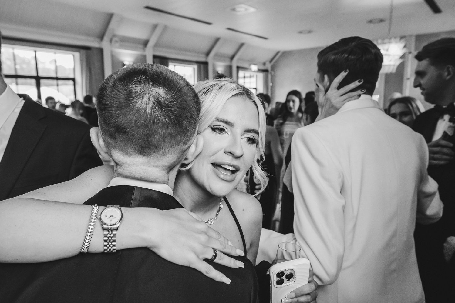 A black and white photo strip showing multiple candid moments of people embracing and celebrating at an event.