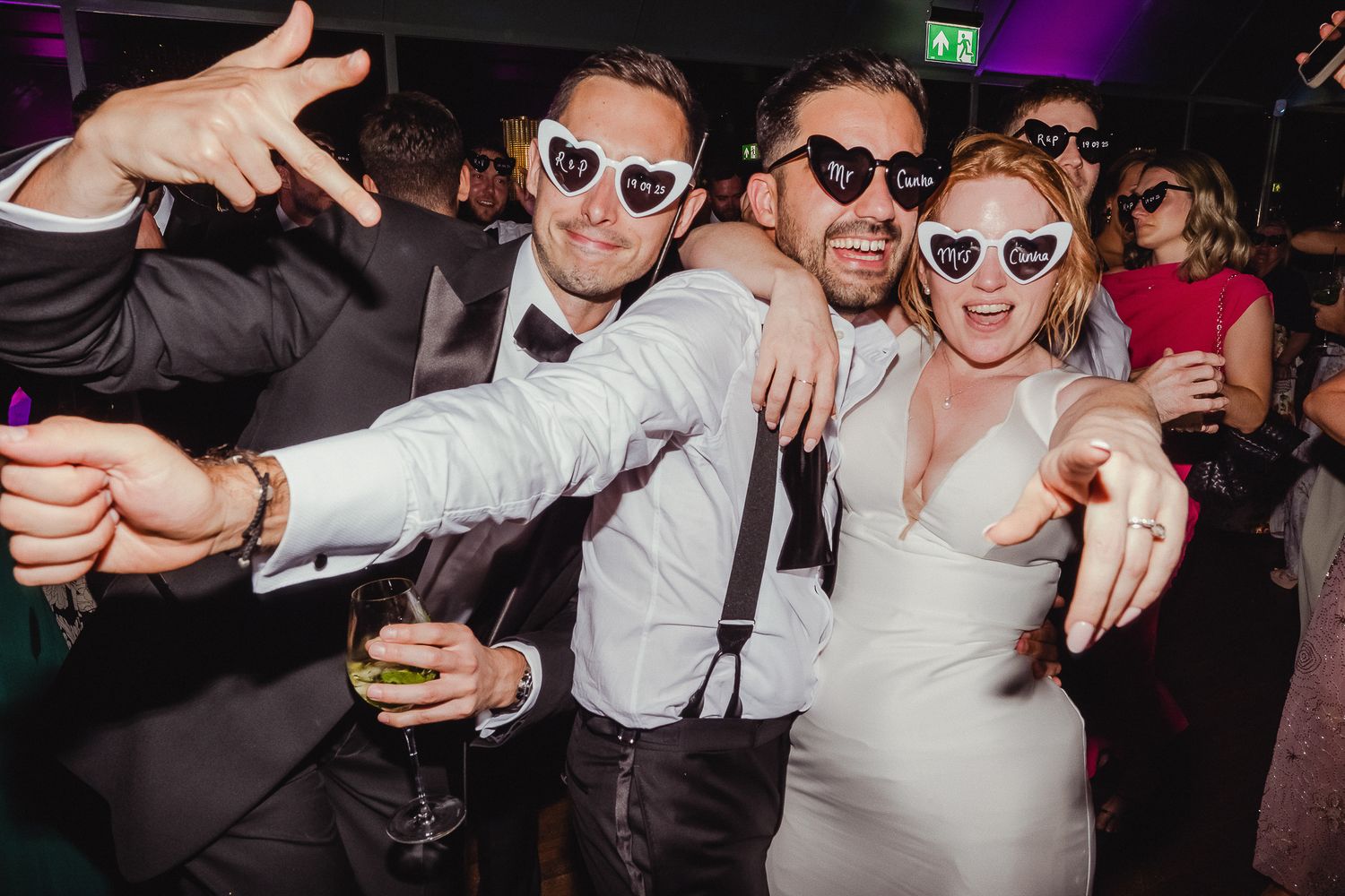 People dancing and celebrating at a lively party with dark lighting and festive atmosphere.