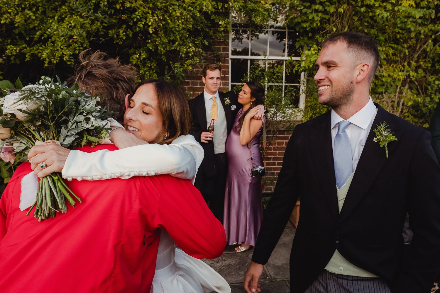 Wedding guests clink champagne glasses together during an outdoor celebration at a garden venue.