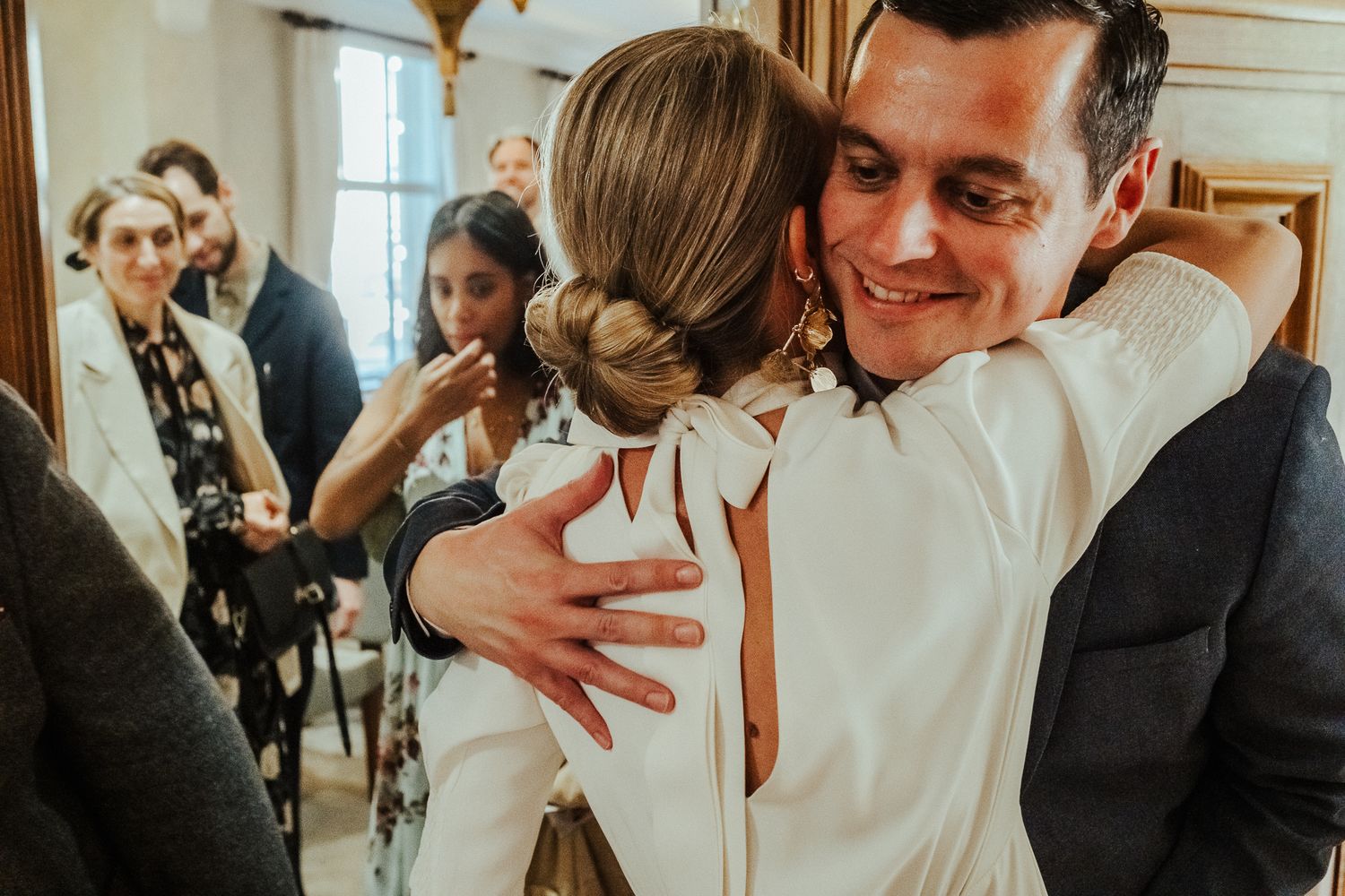 A joyful couple shares tender moments and laughter during an intimate wedding celebration in a bright room.