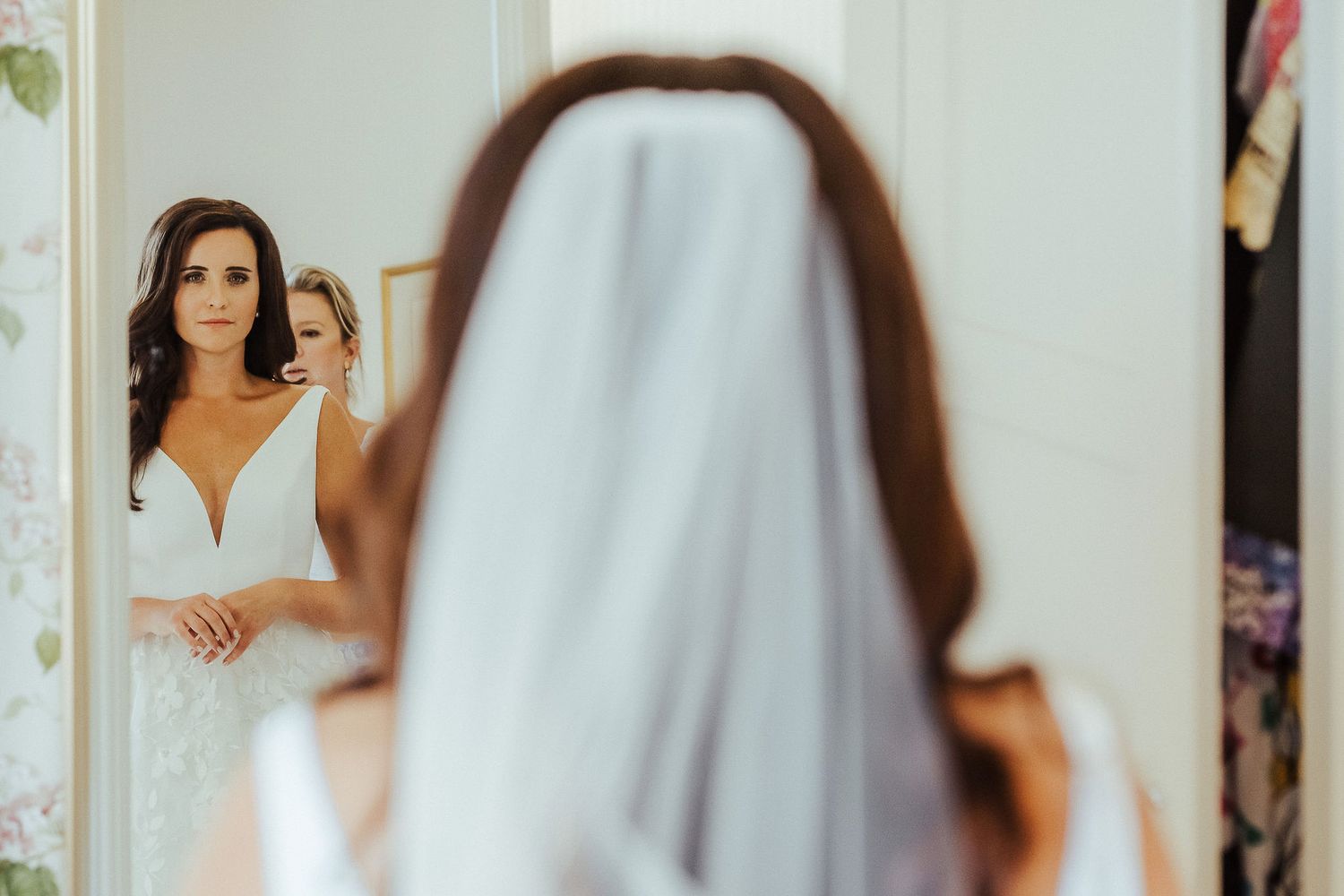 A gorgeous white lace wedding dress being fitted in a brightly lit room.