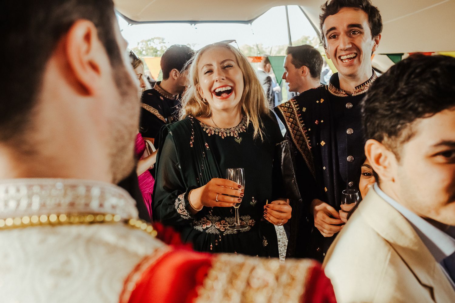 Wedding guests enjoying drinks and laughter at a festive reception celebration.
