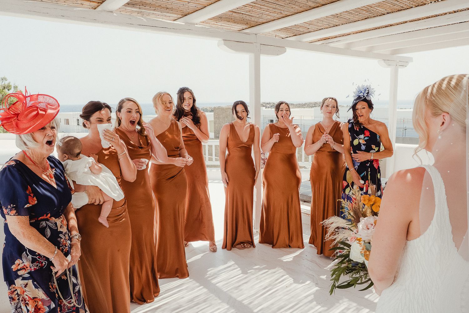 Wedding party members lined up in warm brown dresses celebrate during elegant indoor reception.