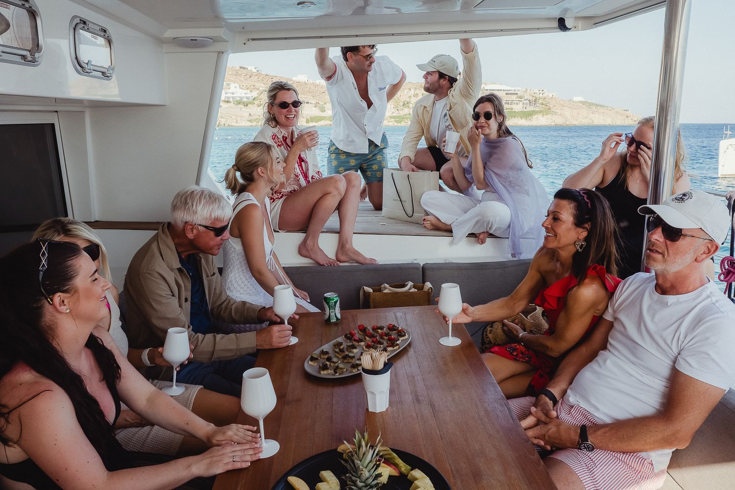 Friends enjoying drinks and conversation while socializing on a boat during a sunny day at sea.