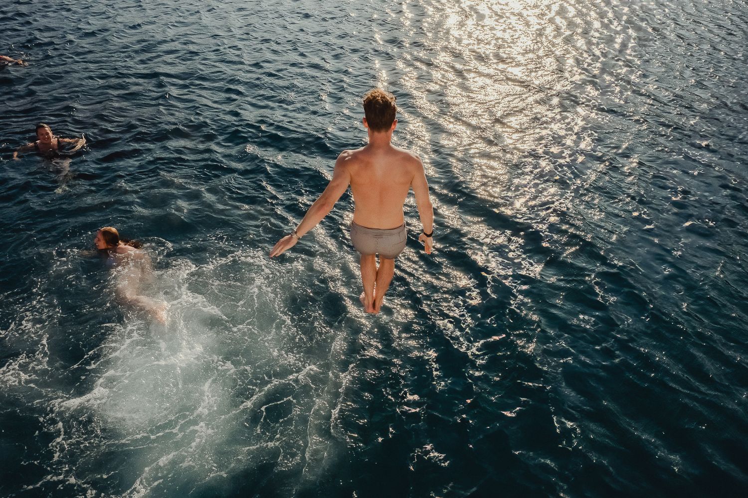 A sequence of photos captures someone jumping into sparkling blue ocean water creating dramatic splashes.