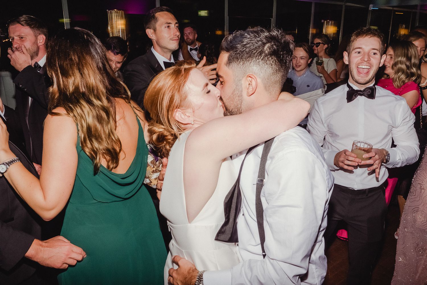 Wedding guests dance and celebrate on a crowded dance floor during an evening reception.