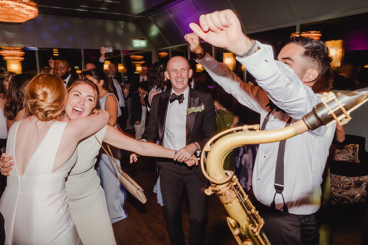 Guests dance and celebrate on a crowded dance floor during a lively wedding reception party.