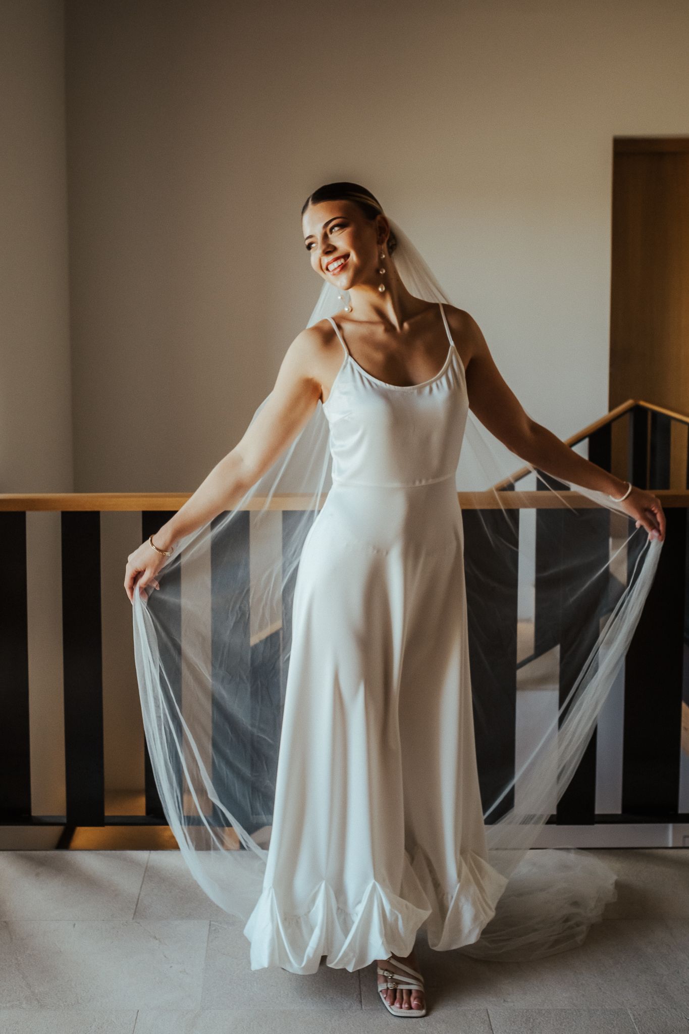 A figure in a flowing white dress and veil creates an ethereal series of dance-like movements in a minimalist room.