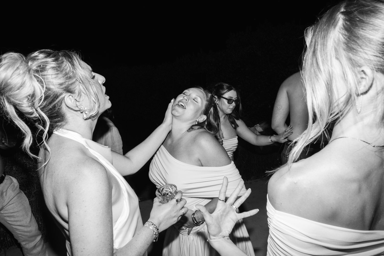 Black and white photo of women dancing and laughing together at a wedding reception party.