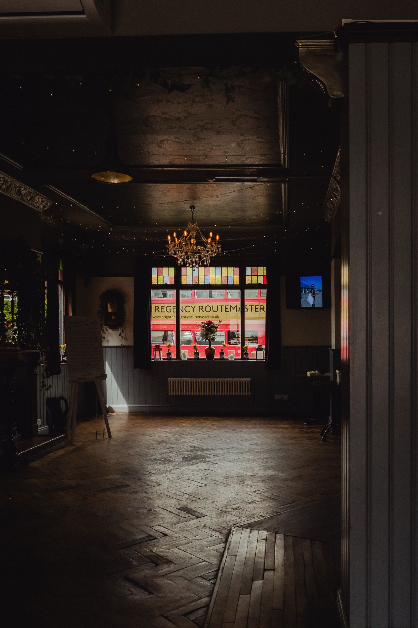 Dark empty warehouse interior with bright colorful stained glass windows casting light across wooden floors.