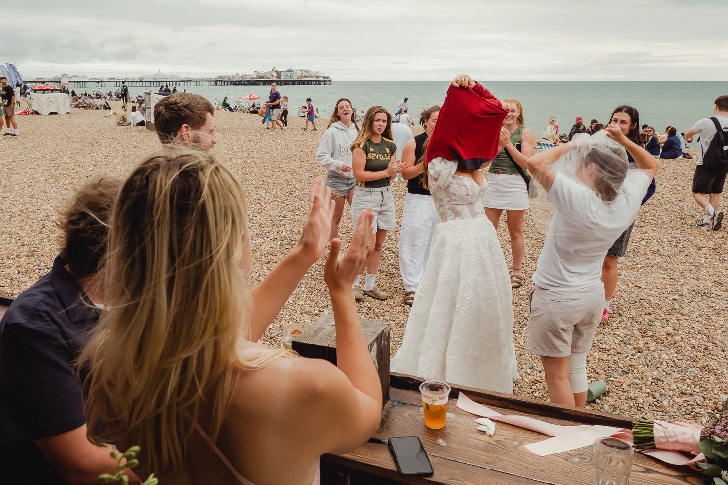 A group of people in white dresses gather together on a beach during a sunny day.