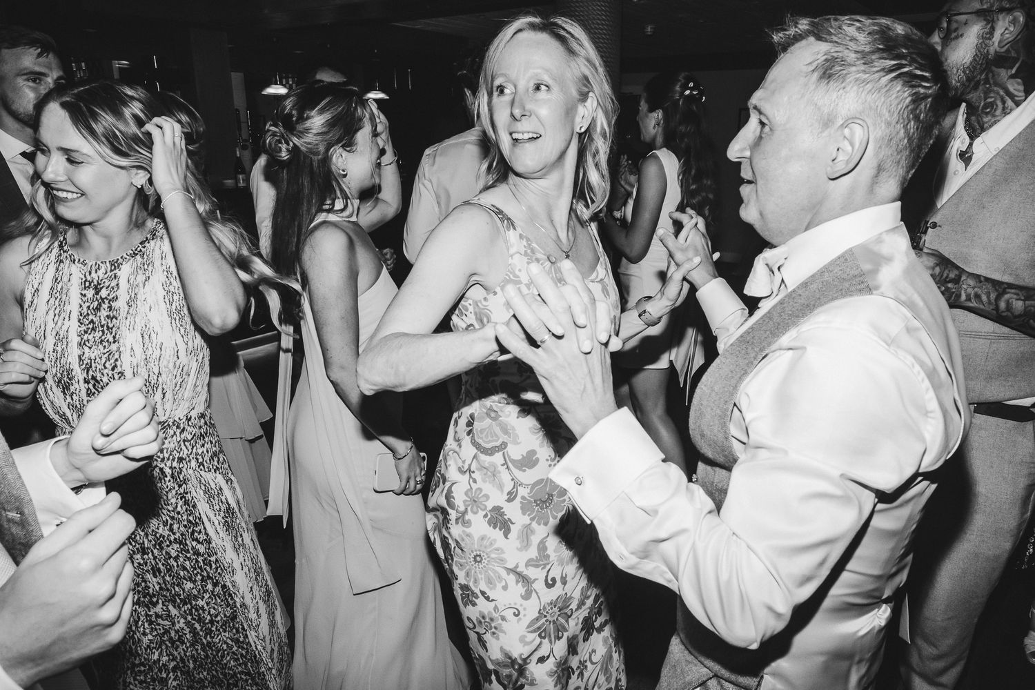 Wedding guests dancing and celebrating together on a crowded dance floor at a reception party.