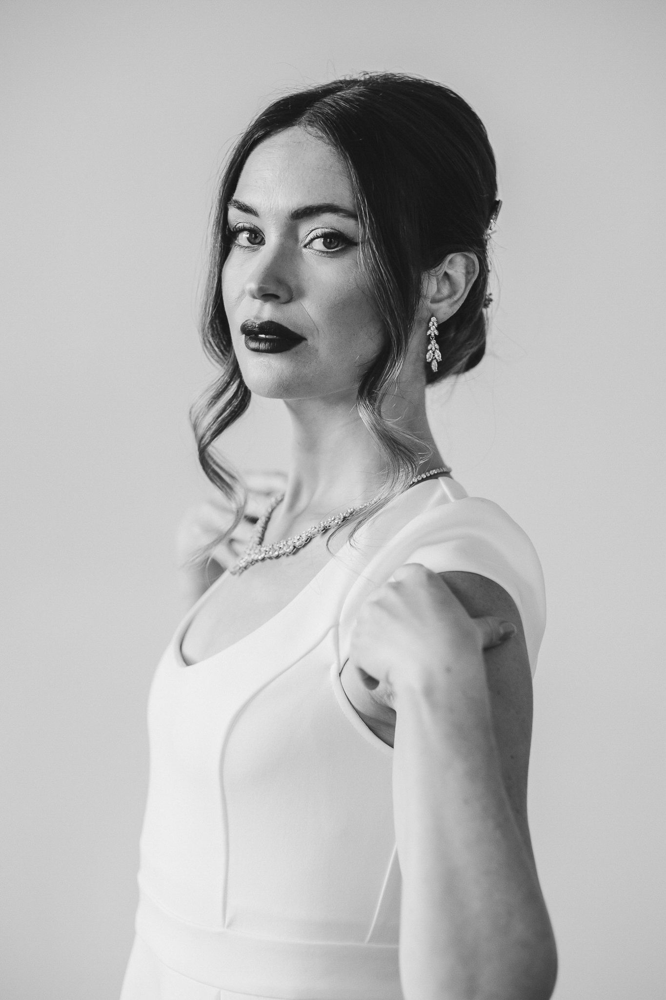 Black and white portrait series showing a woman in a white sleeveless top posing with dramatic lighting and makeup.