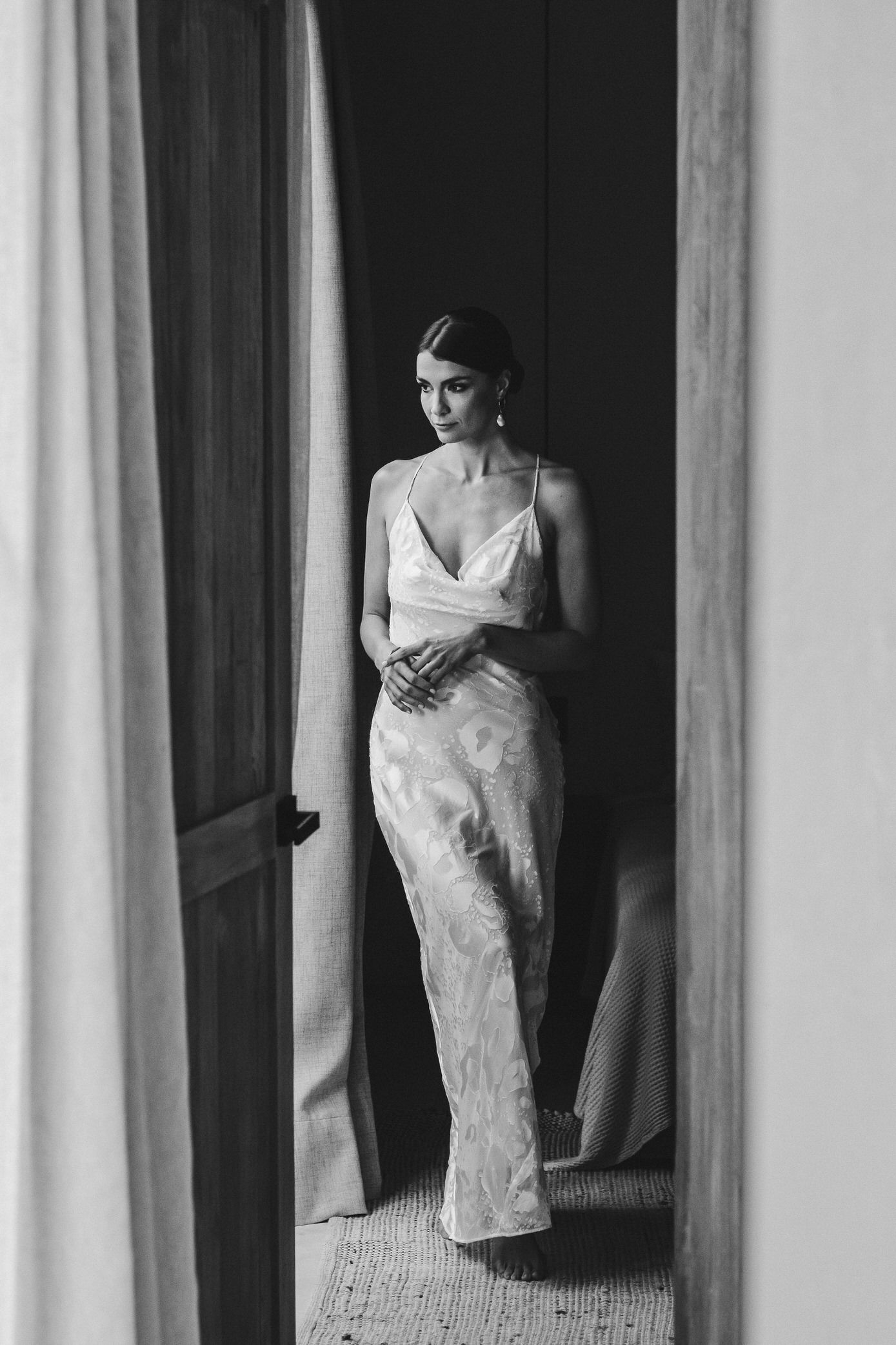 A series of black and white photographs showing a person in a white dress against dark vertical panels.