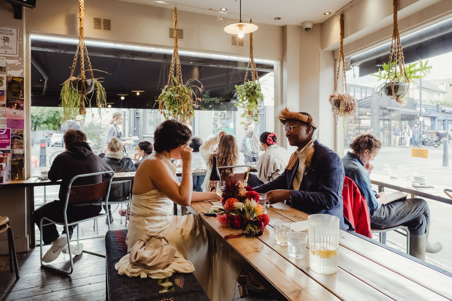 A panoramic view of a modern wine bar interior with hanging plants and natural lighting.