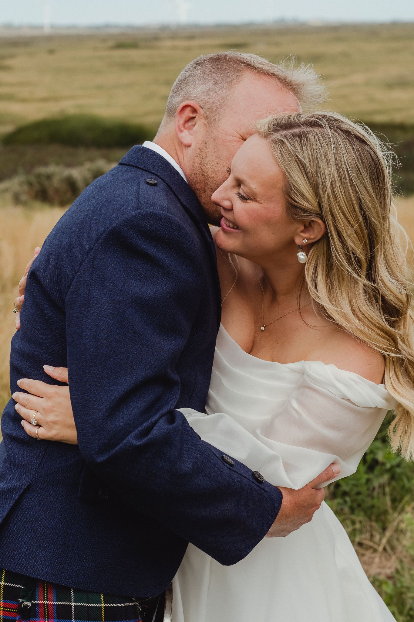 A romantic sequence of wedding photos showing a couple embracing and kissing in a scenic outdoor field setting.