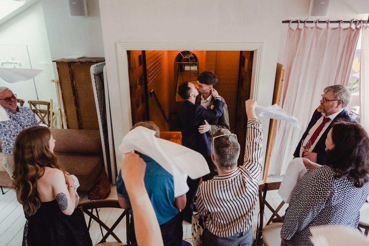 Several people gather in a tight space as they interact and converse during an indoor social event.