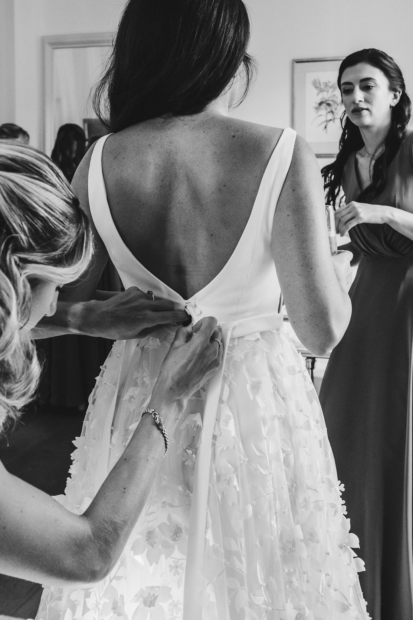 Black and white photo of wedding dress details being adjusted before the ceremony.
