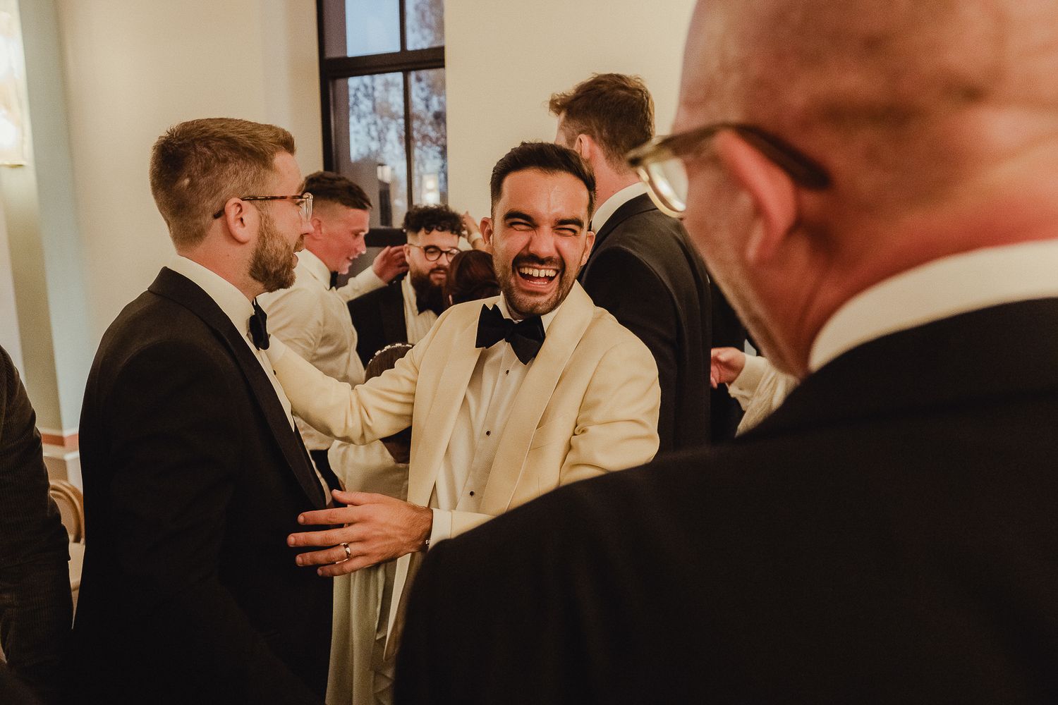 A group of people in formal attire mingle and converse during an elegant indoor event.