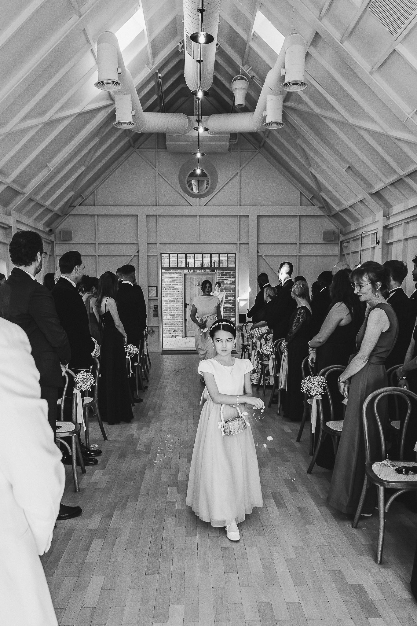 A black and white photo series showing a wedding ceremony procession in a small chapel with vaulted ceilings.