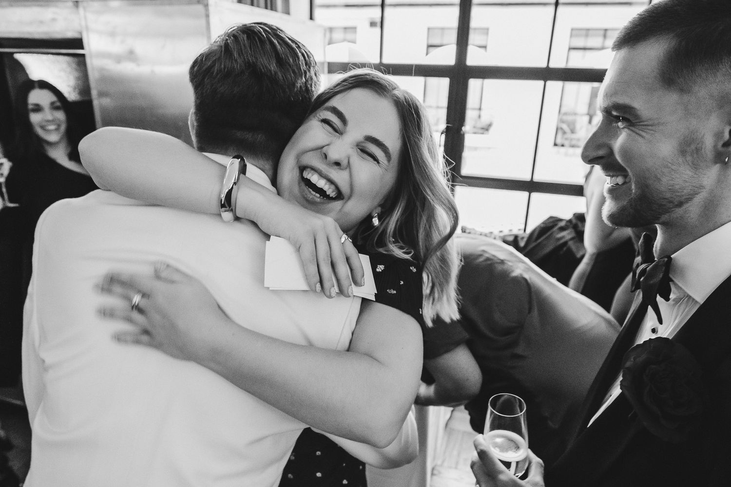 A series of black and white photos showing joyful moments and embraces at what appears to be a wedding celebration.