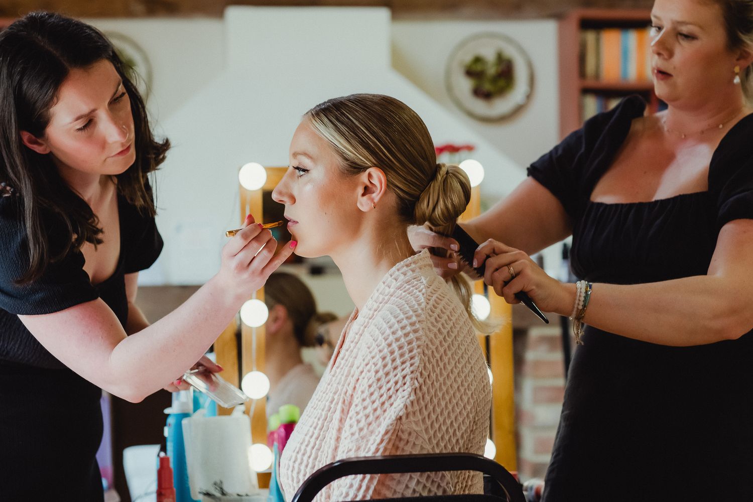 Professional makeup artist working on wedding day beauty preparation with brushes and cosmetics.