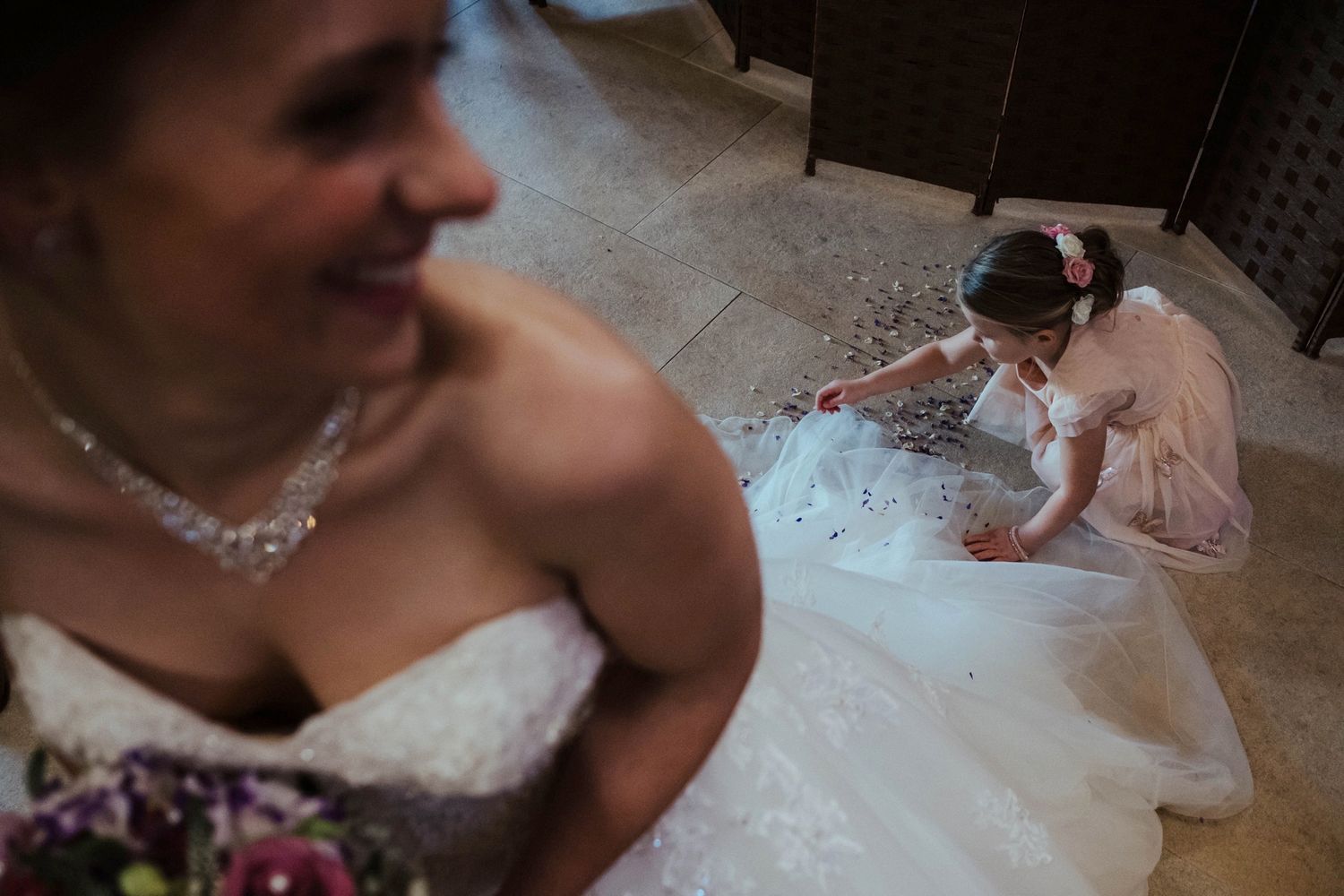 Wedding dress detail with a young attendant playing with the gown's fabric.