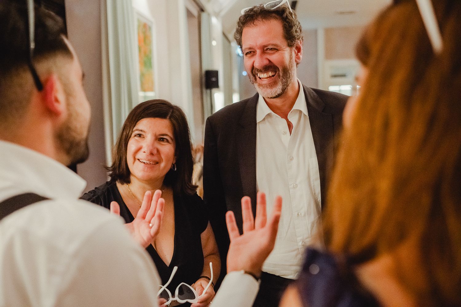 A group of people laughing and socializing at an indoor gathering, creating a warm and joyful atmosphere.