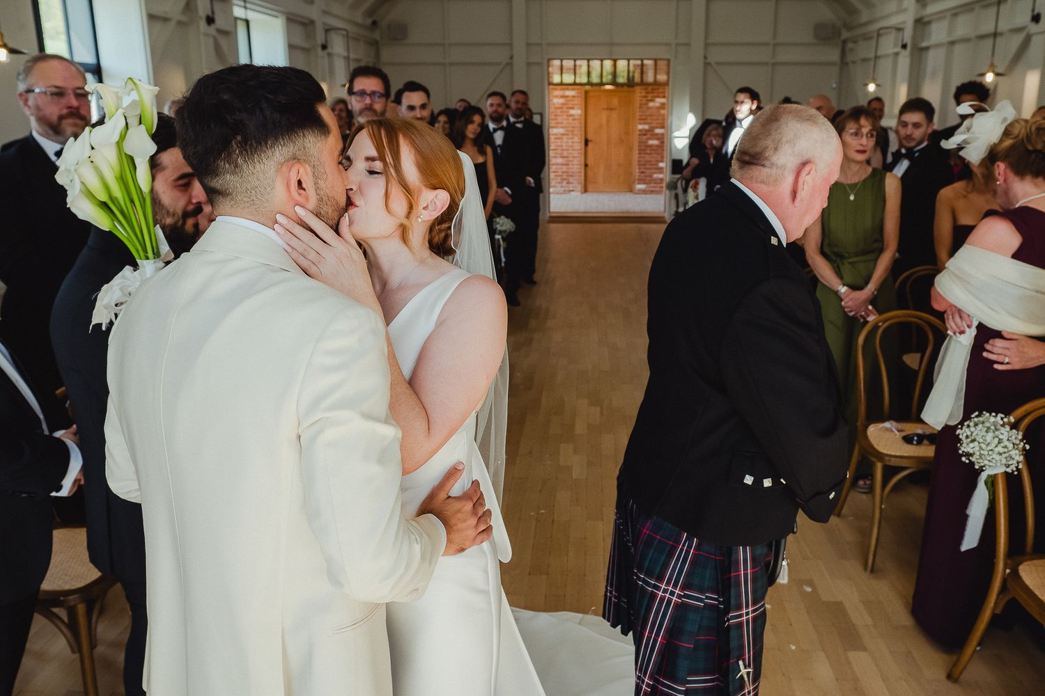 A couple shares their first dance at a wedding reception in an elegant indoor venue with guests watching.