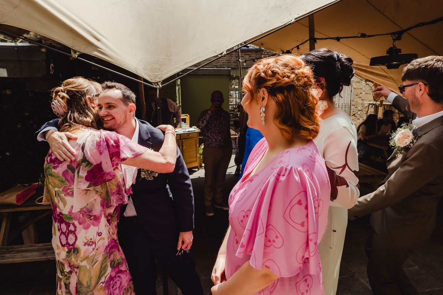 Couples dance together in formal attire at an elegant ballroom event with pink floral decorations.