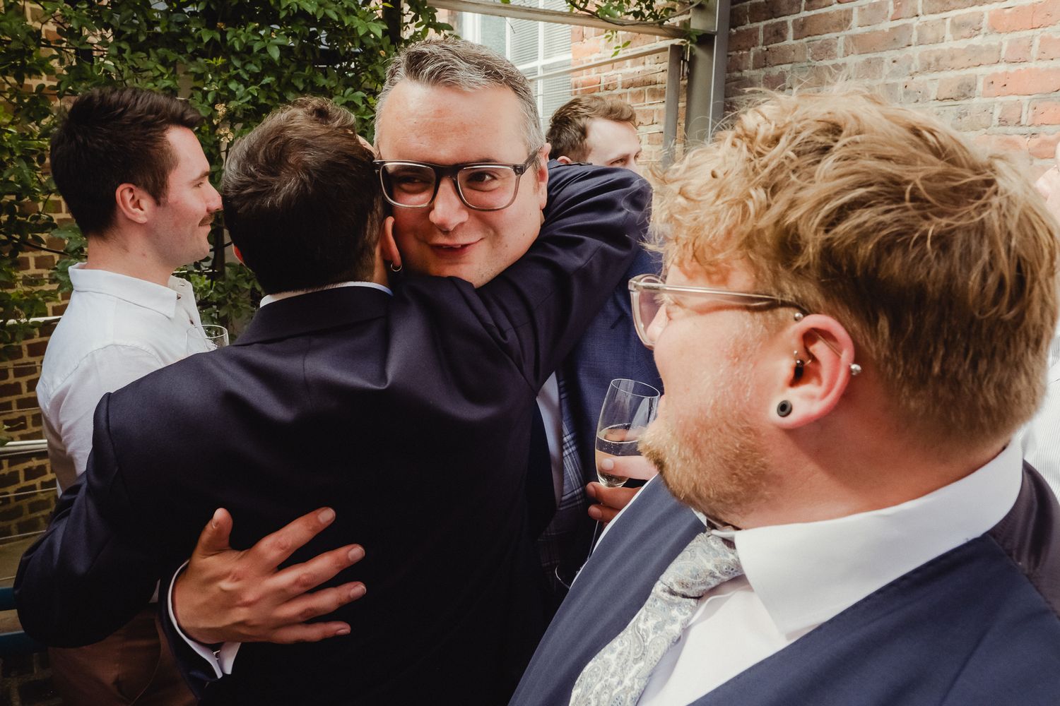 A series of candid moments showing people embracing and sharing emotional hugs at a gathering.