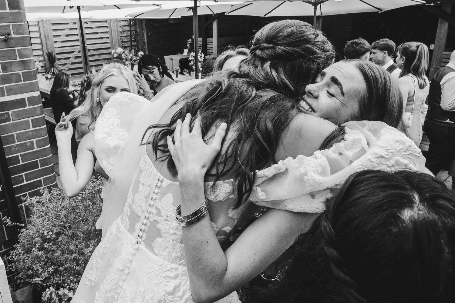 Black and white photo of wedding guests hugging and celebrating at a reception.
