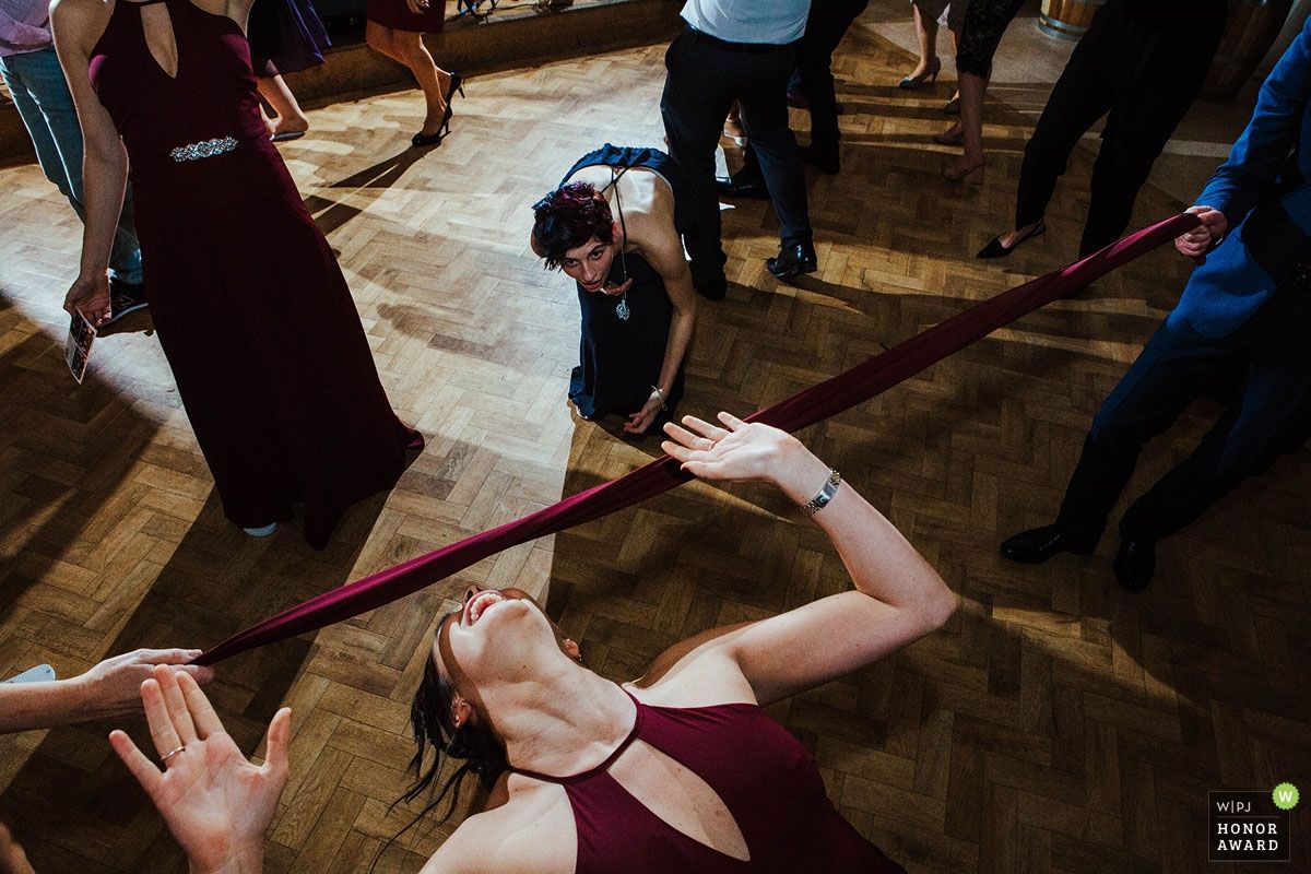 Wedding reception guests dancing and celebrating on a dark wooden dance floor.