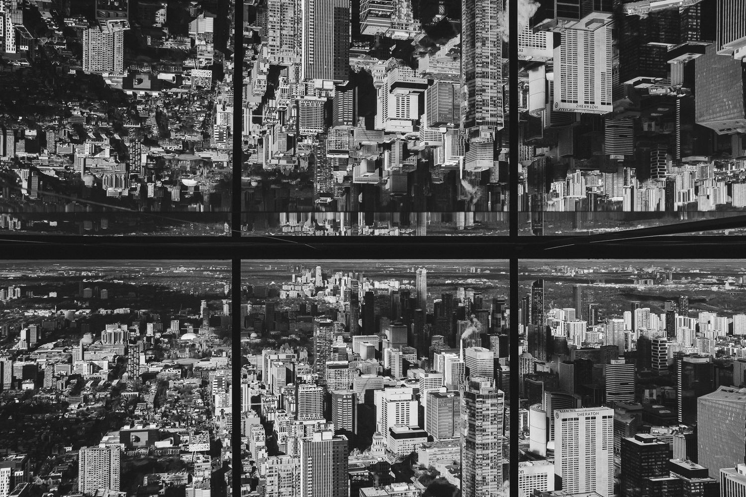 Aerial black and white panoramic view of a dense urban cityscape with tall buildings and skyscrapers stretching to horizon.