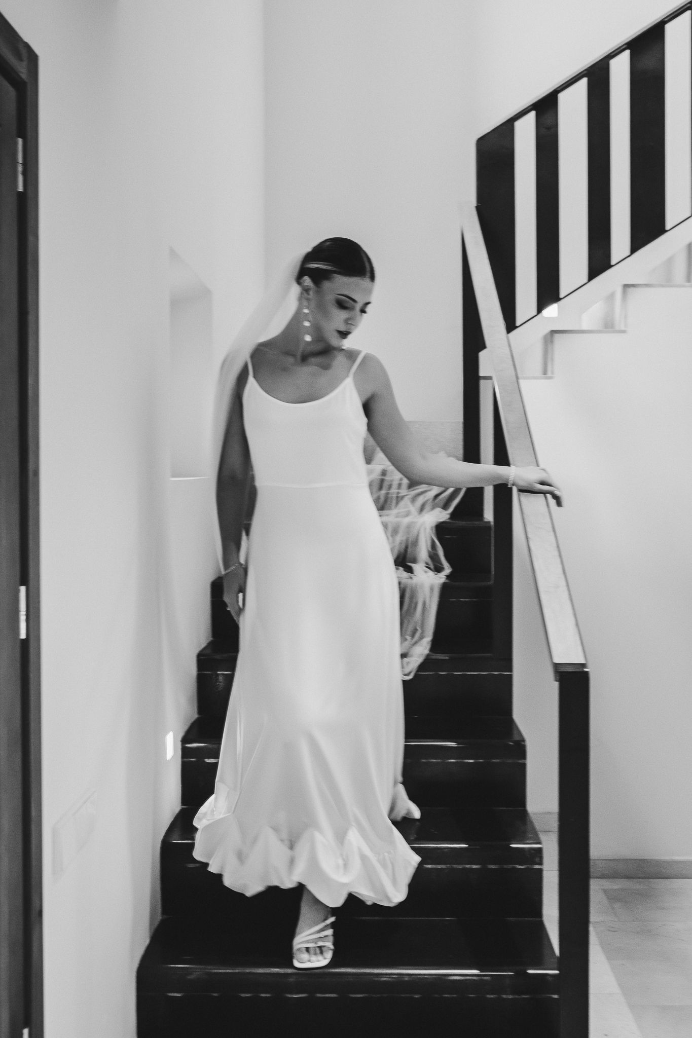 A sequence of black and white photos showing someone in a white dress walking down stairs.