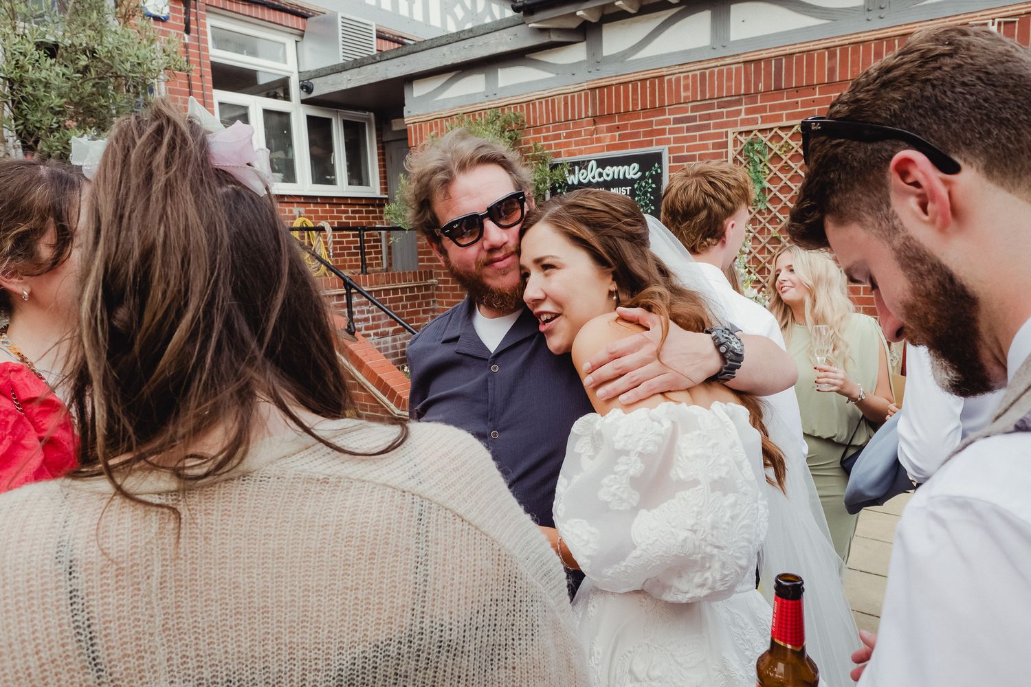 A joyful gathering of people celebrating at an outdoor party with brick walls and casual atmosphere.