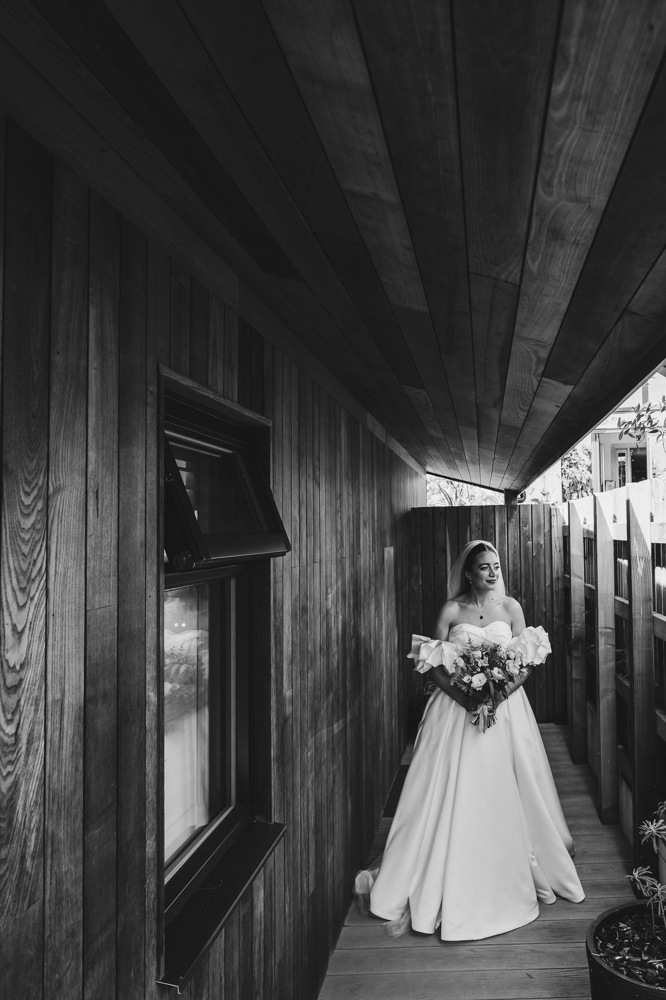 A black and white photo series showing a person in a wedding dress walking through a wood-paneled hallway.