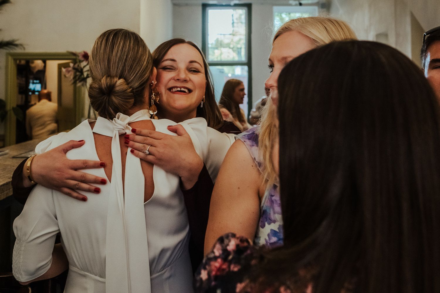 Joyful celebration at an indoor gathering with people embracing and sharing warm moments together.