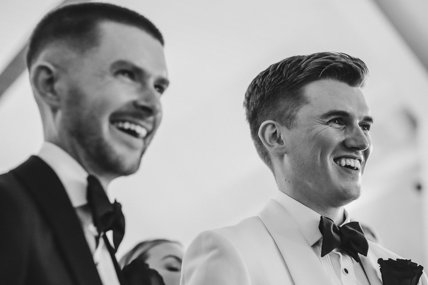 A series of black and white photos showing joyful expressions and laughter at a wedding celebration.