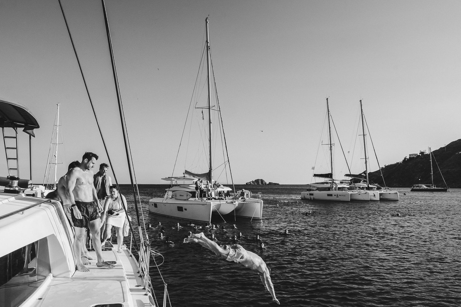 A series of black and white photographs showing boats and sailboats anchored in a marina during a sunny day.