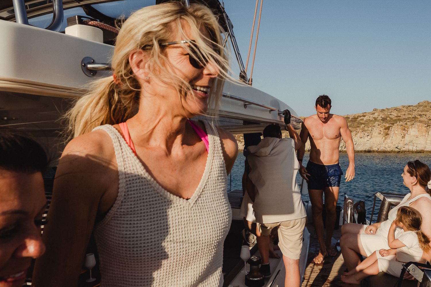 A group enjoys an outdoor beach gathering at sunset with vintage camper vans parked nearby in a scenic desert location.