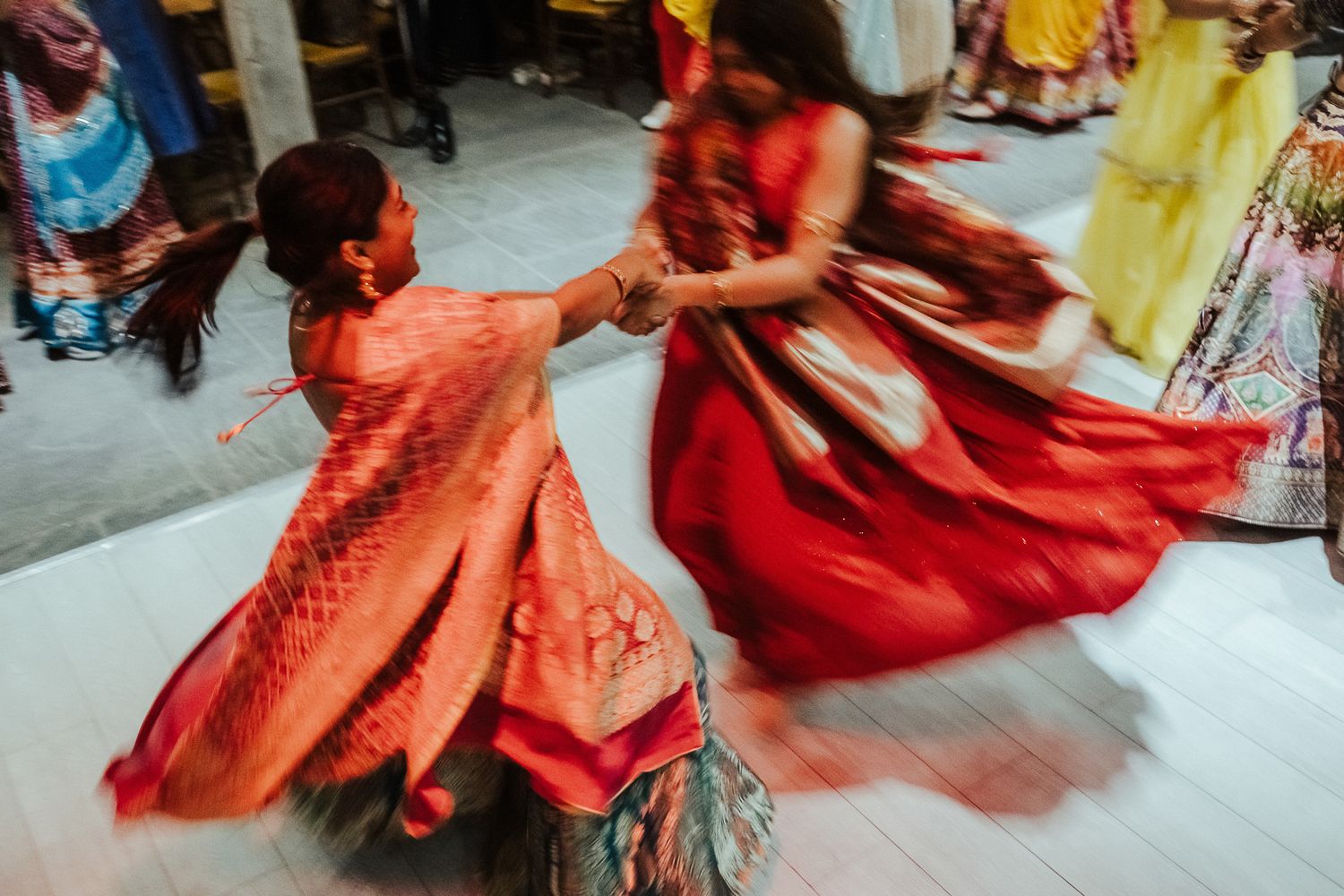 Dancing couple in vibrant red and orange outfits twirling on dance floor.