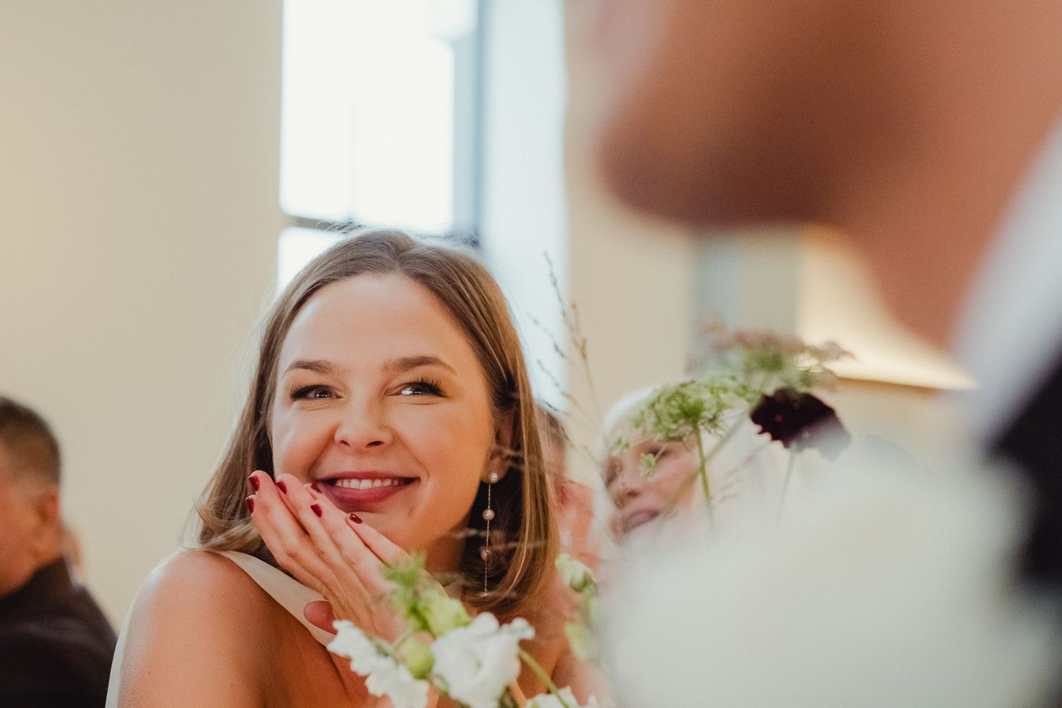 A group of people gather around a table at a wedding reception, enjoying conversation and laughter together.