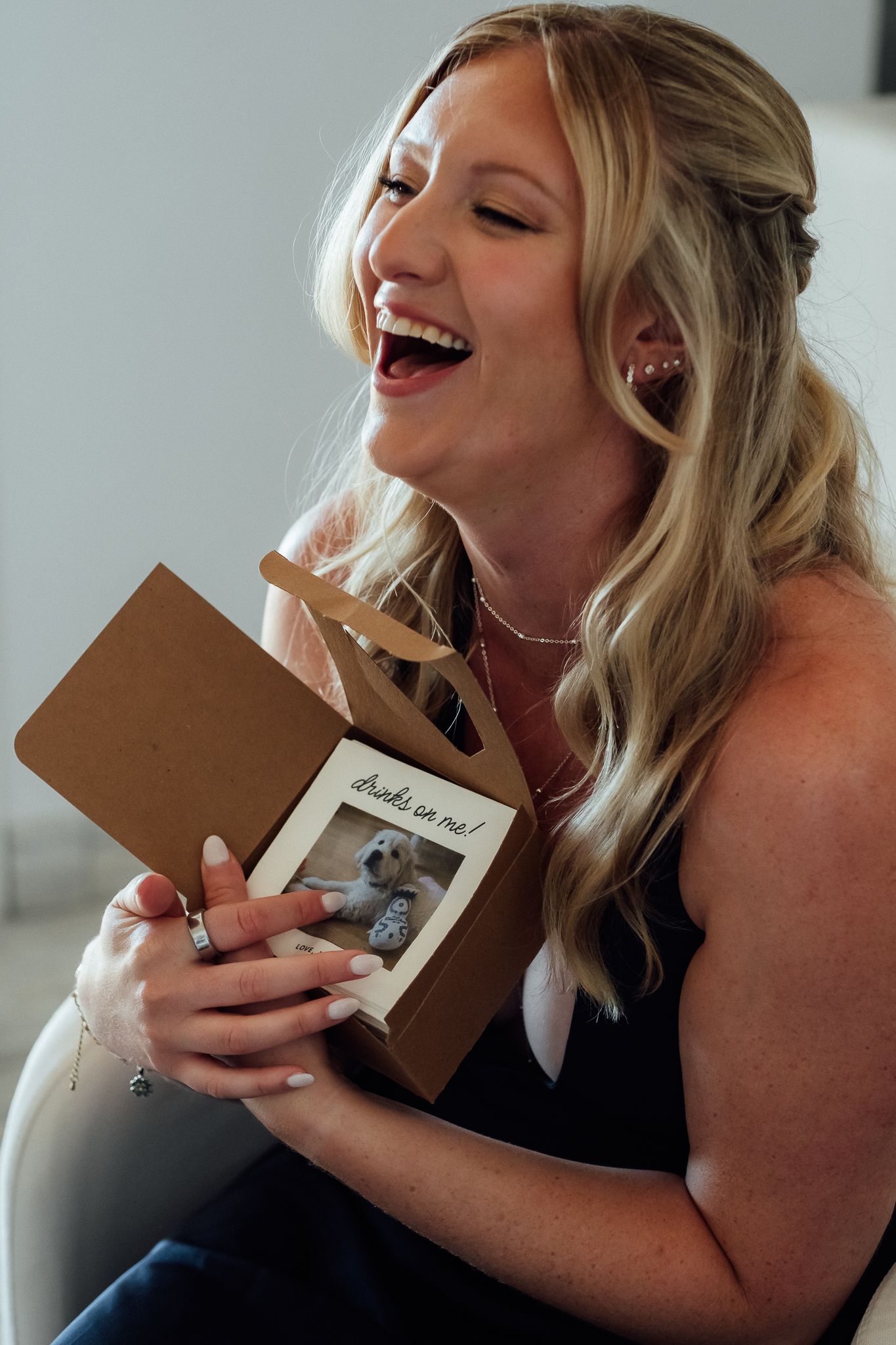 Laughing blonde woman holding a kraft gift box with a dog photo and 