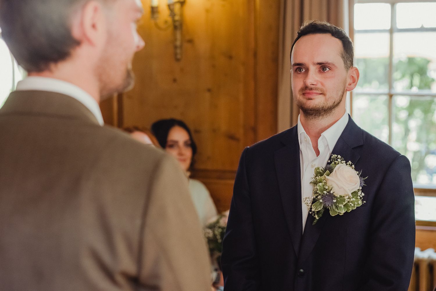 A couple exchanges rings during an intimate indoor wedding ceremony in a rustic wooden venue.