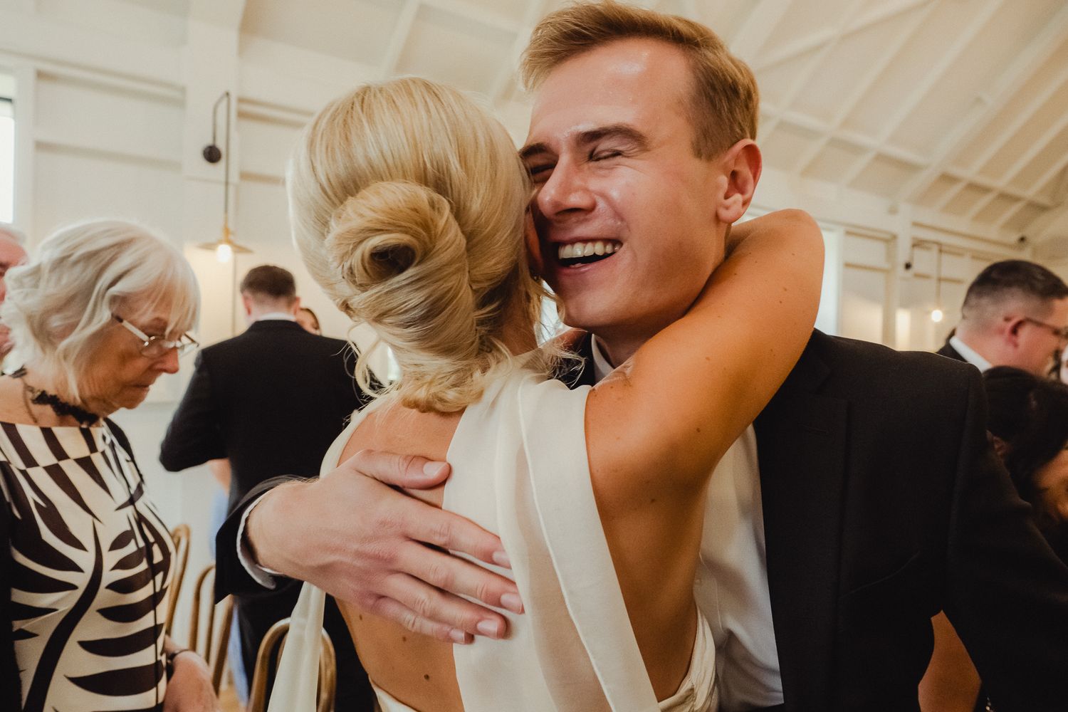 A series of candid moments showing joyful embraces and laughter at an indoor celebration event.