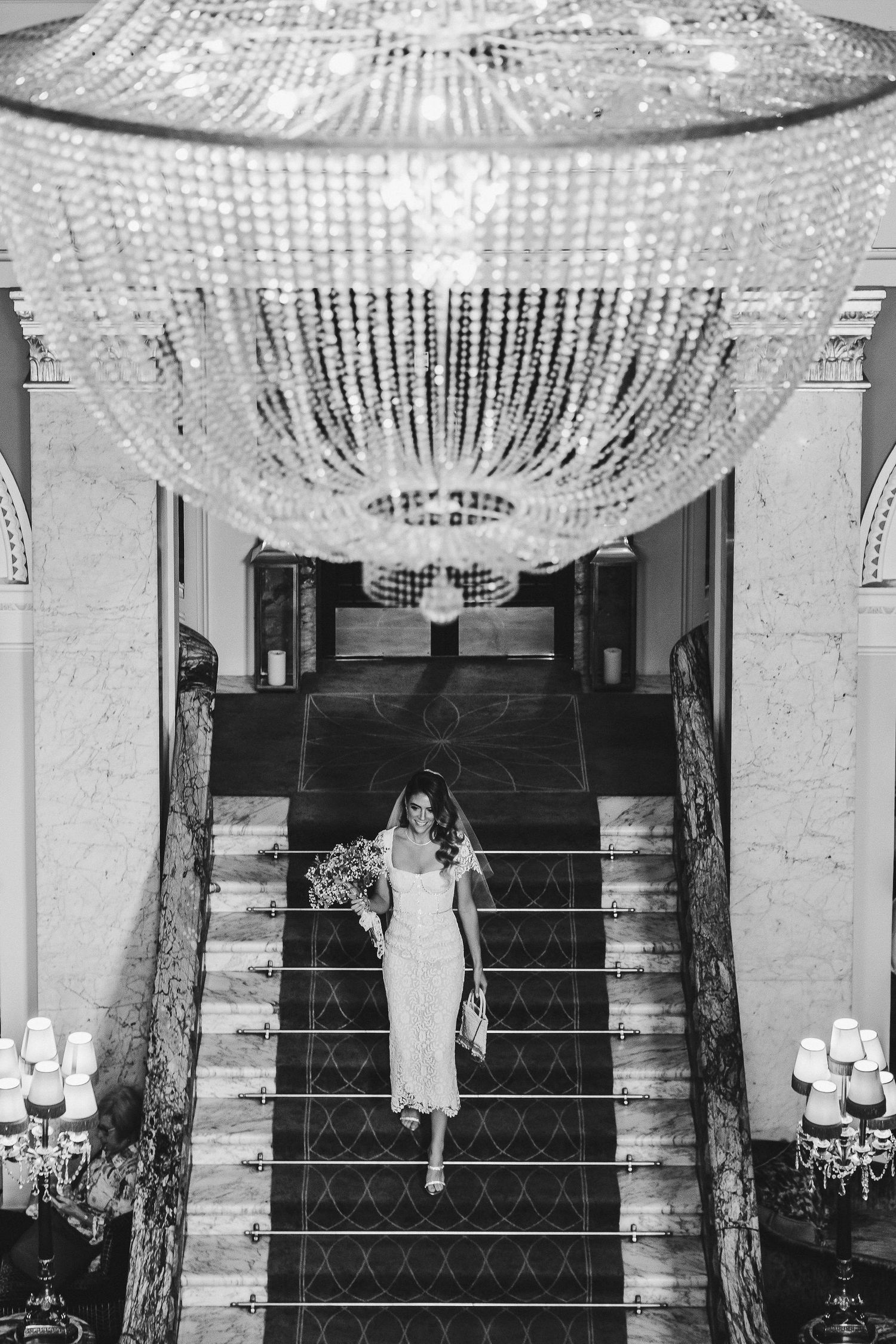 A sequence of black and white photos showing a person standing on stairs under an elegant crystal chandelier.