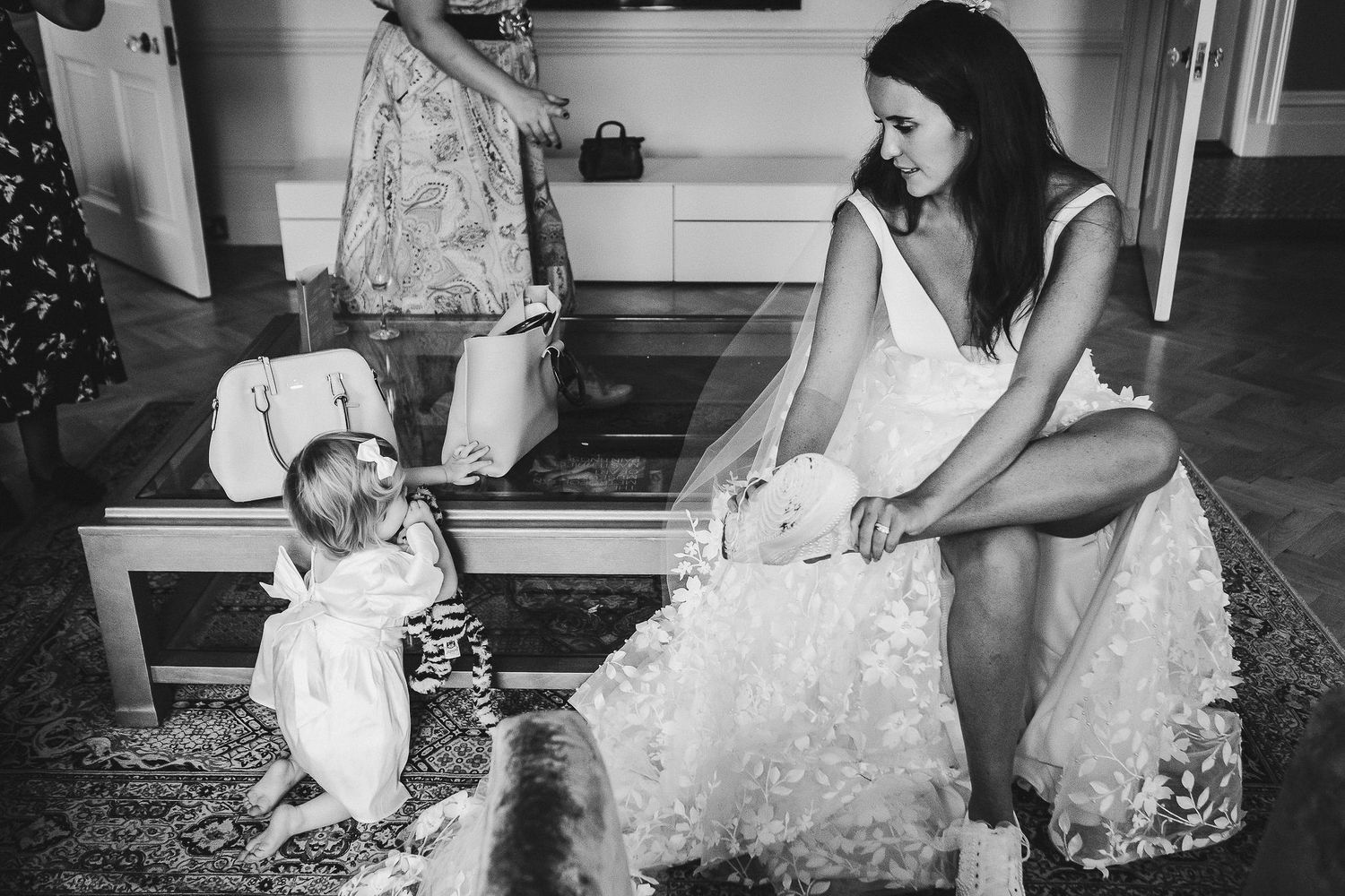 A candid black and white moment showing a toddler and woman in a wedding dress.