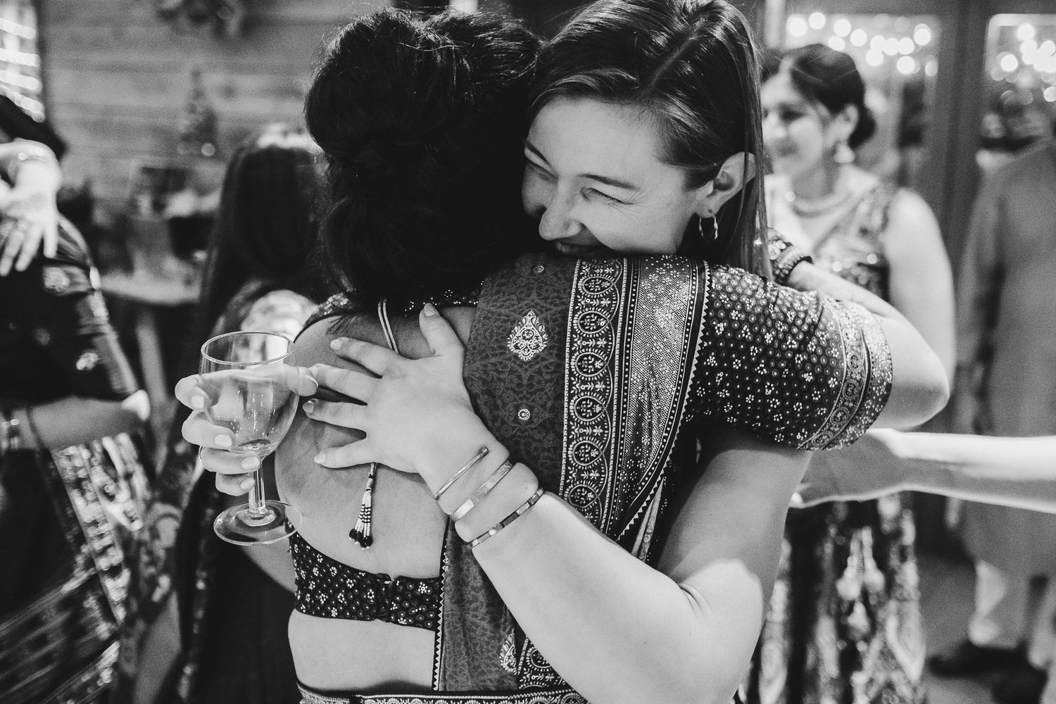 Emotional embrace between guests wearing traditional Indian attire at a celebration.